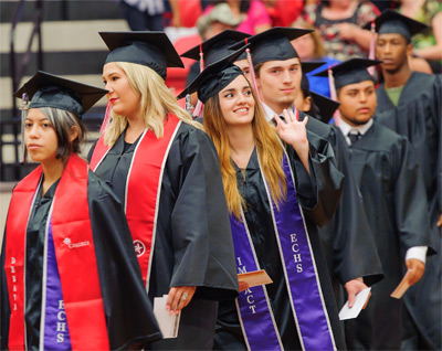 Students walk in cap and gown during commencement