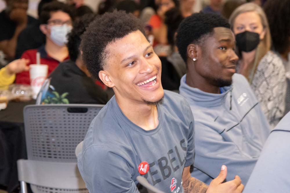 Students and employees seated and smiling at an orientation session.