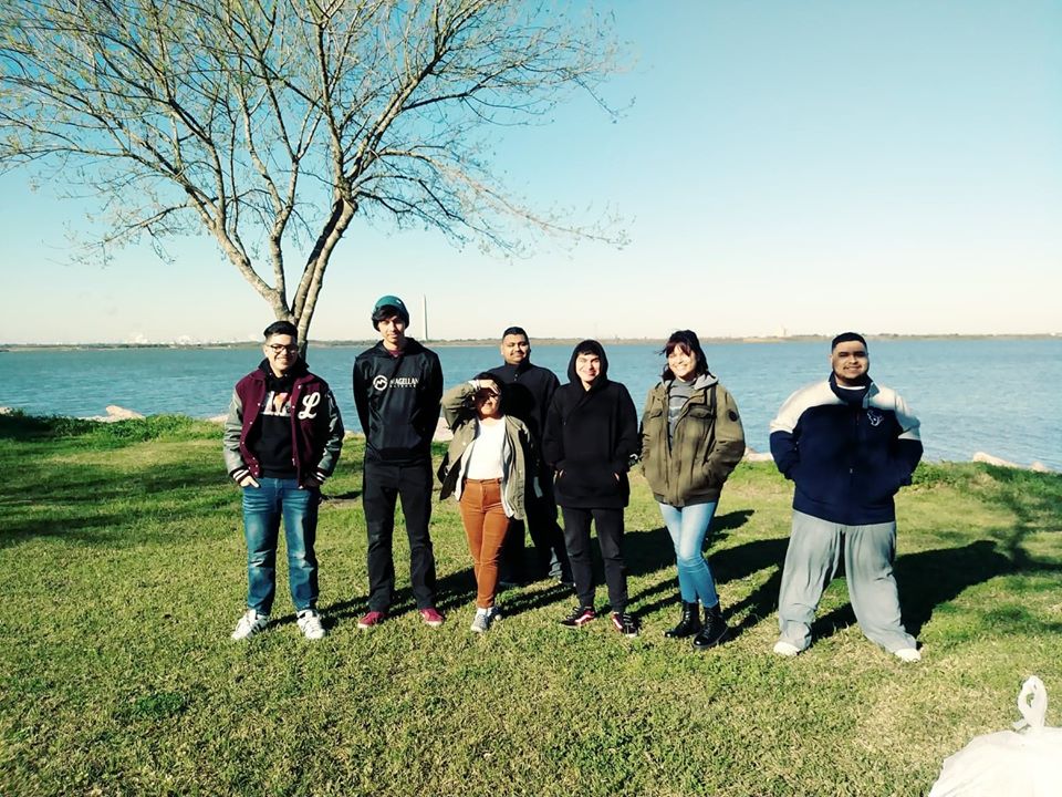 Seven students pose with a body of water behind them