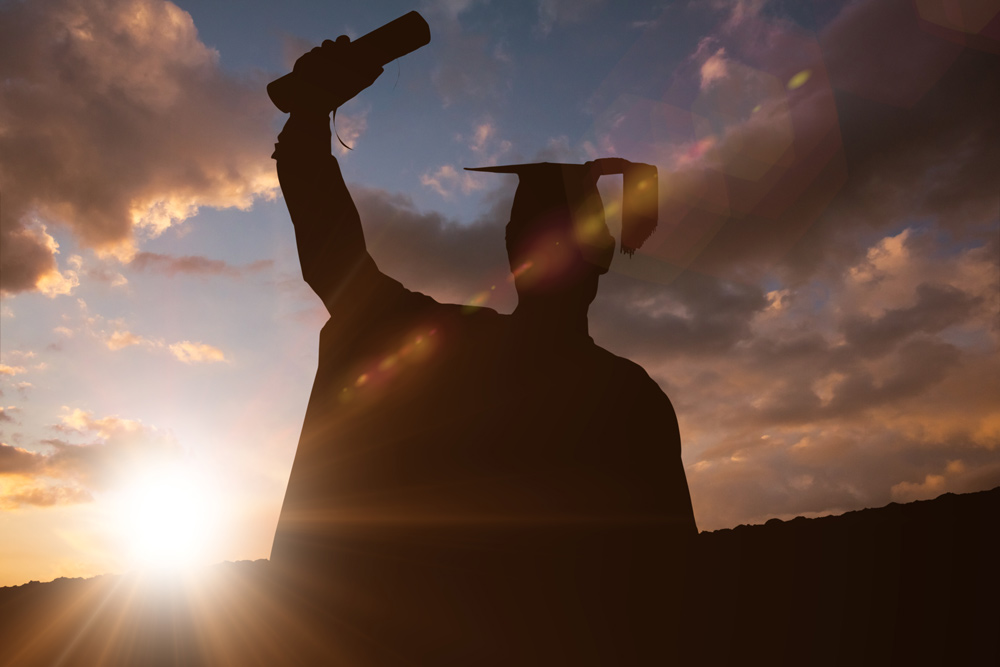 Silhouette of male graduate against colorful sunset