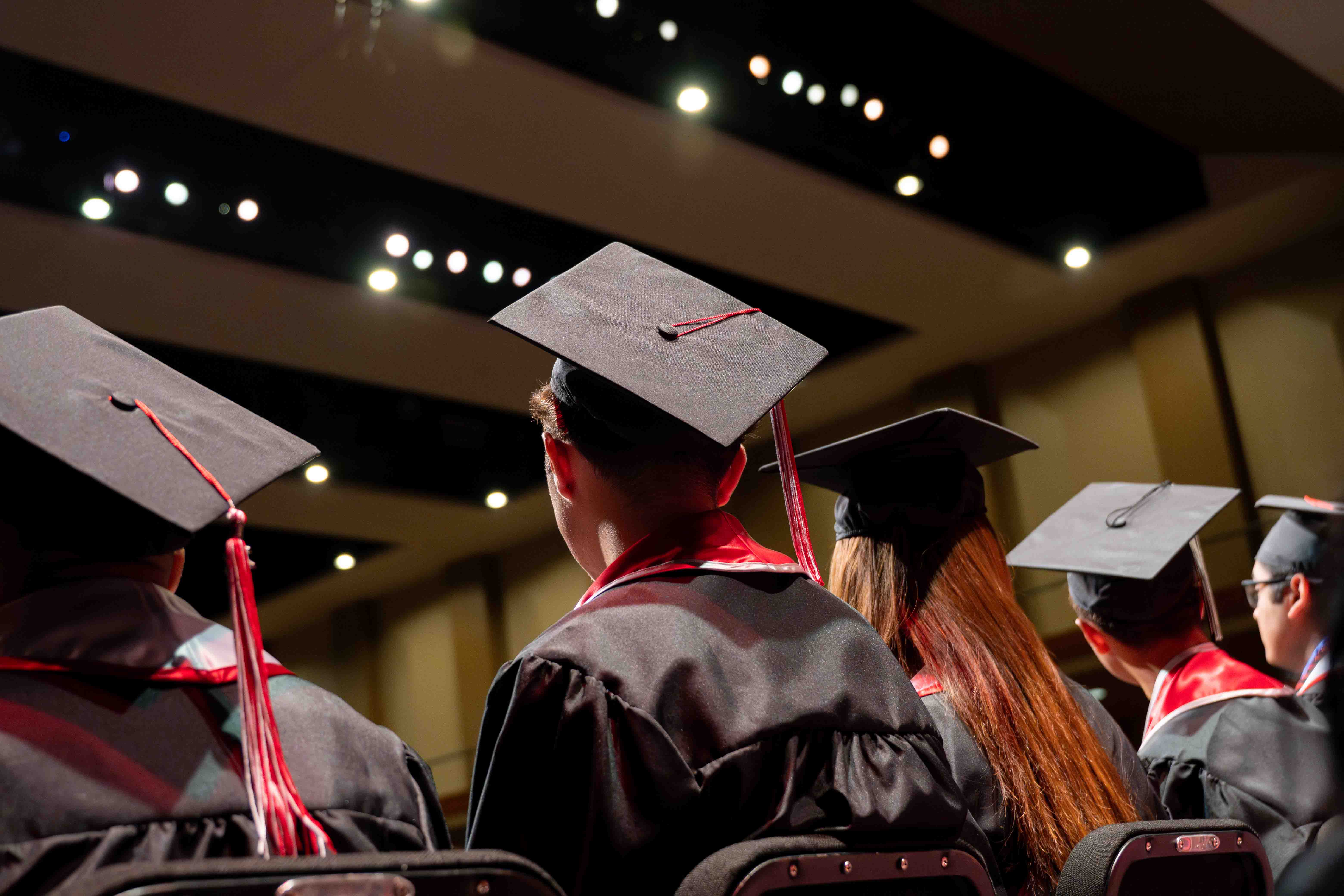 Graduates are on stage in the lights of the Performing Arts Center.