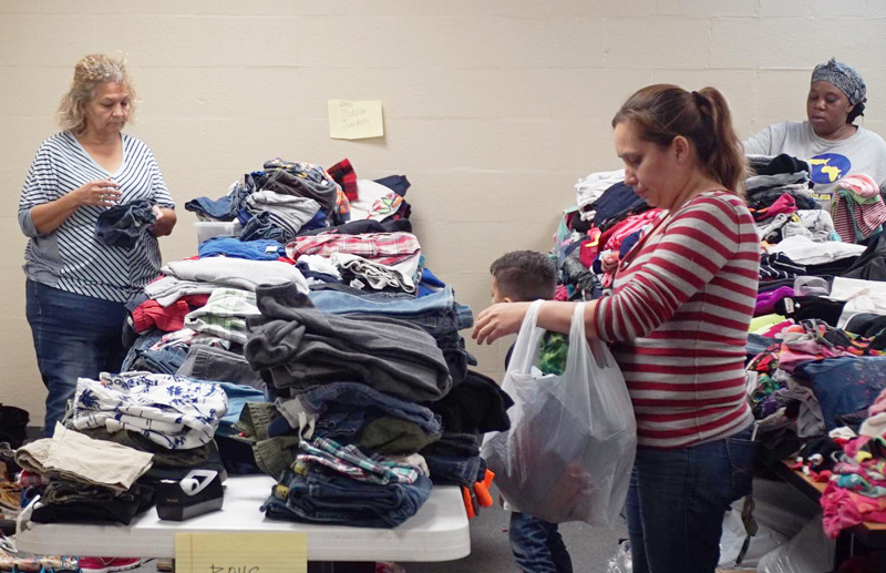 Women in the shelter sort through tables of clothing.