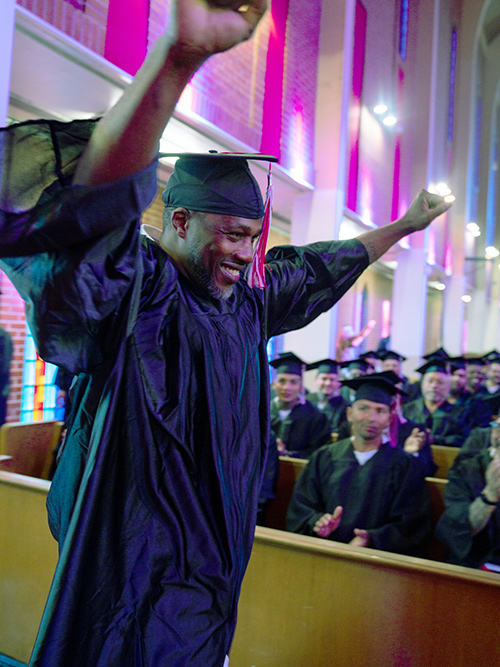 An exuberant graduate crosses to receive his diploma.