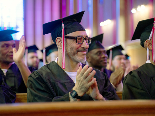 Seated graduates smile and applaud.