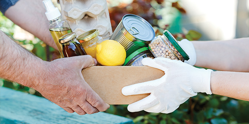 Gloved hands place a box of food items in another set of hands