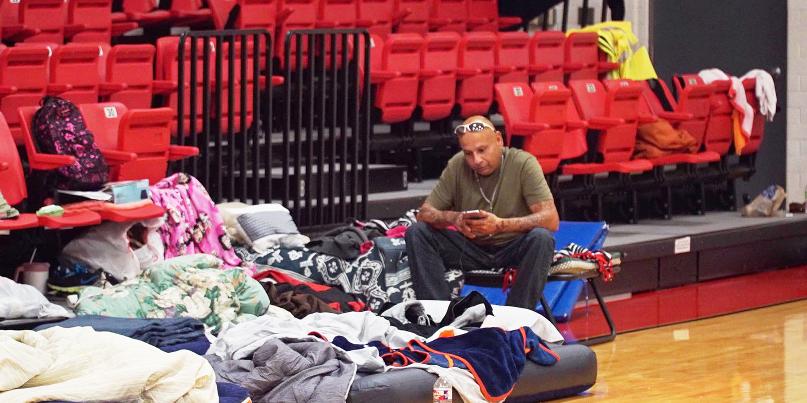 A man in Lee College's shelter somberly checks his cell phone.