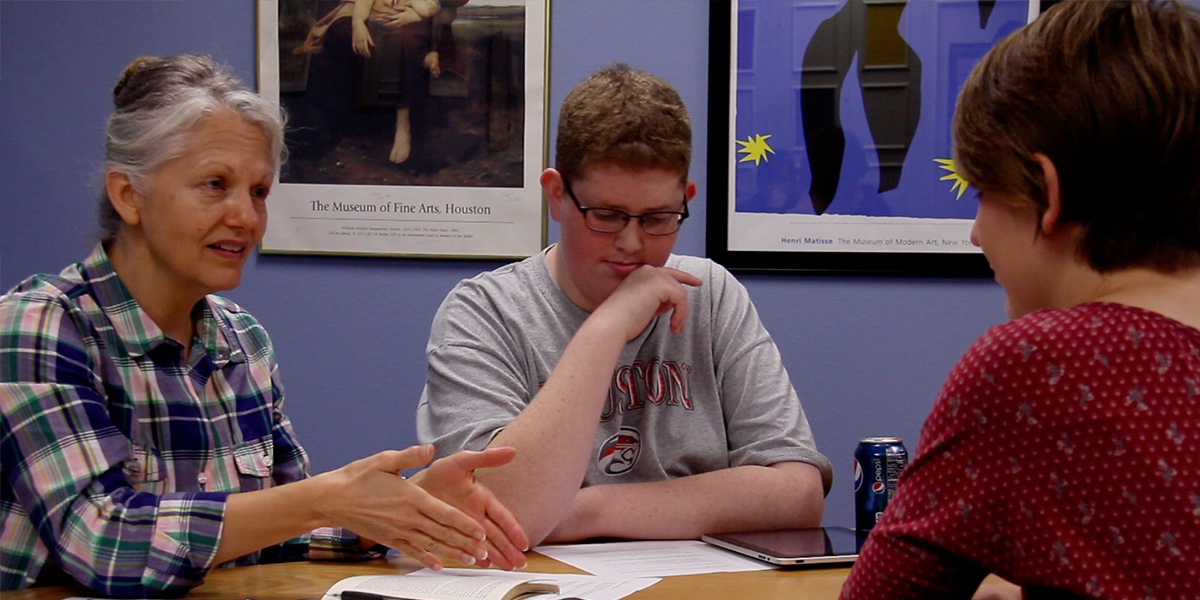 Former Lee College students Debbie Long, Christian Morrell, and Jessie Selph talk at a classroom table.