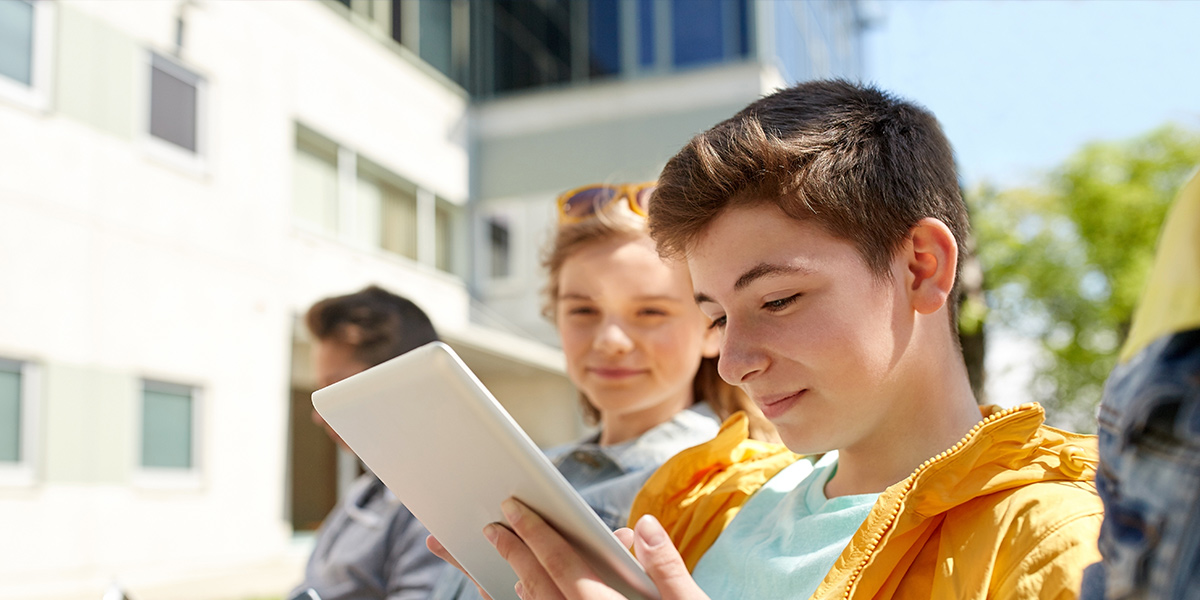 Two high school students reading outside on an electronic device