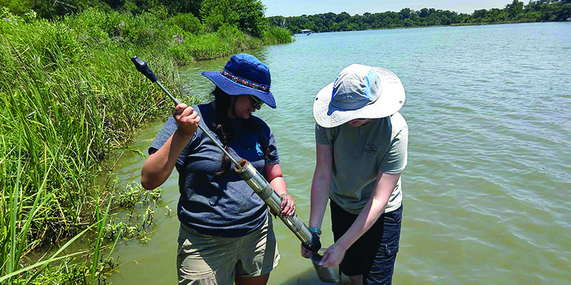 Emily Macias and a fellow student collect a soil sample.