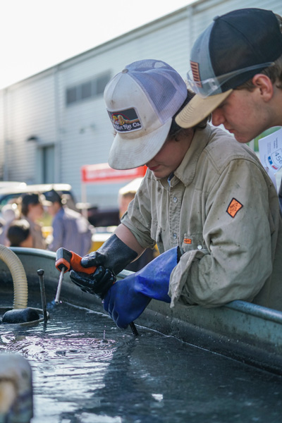 Two young welders work over a tub of water.