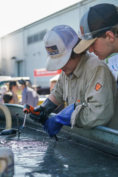 Two young welders work over a tub of water.