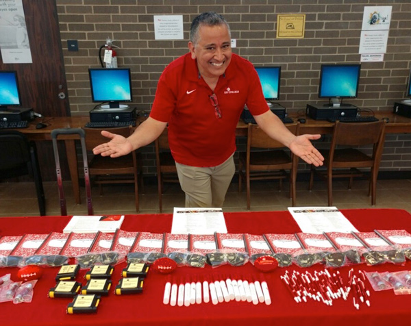 A smiling Lee College employee at an exhibit table with promotional items