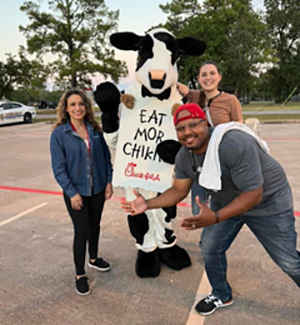 Three people have fun with the Chick-fil-A cow mascot