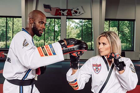 A man and woman practice sparring in a martial arts setting