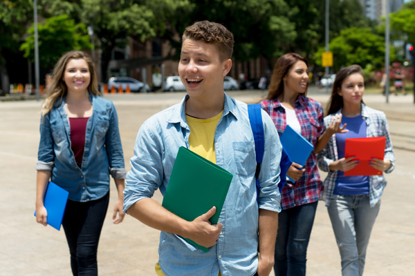 A smiling college freshman with several other students in the background